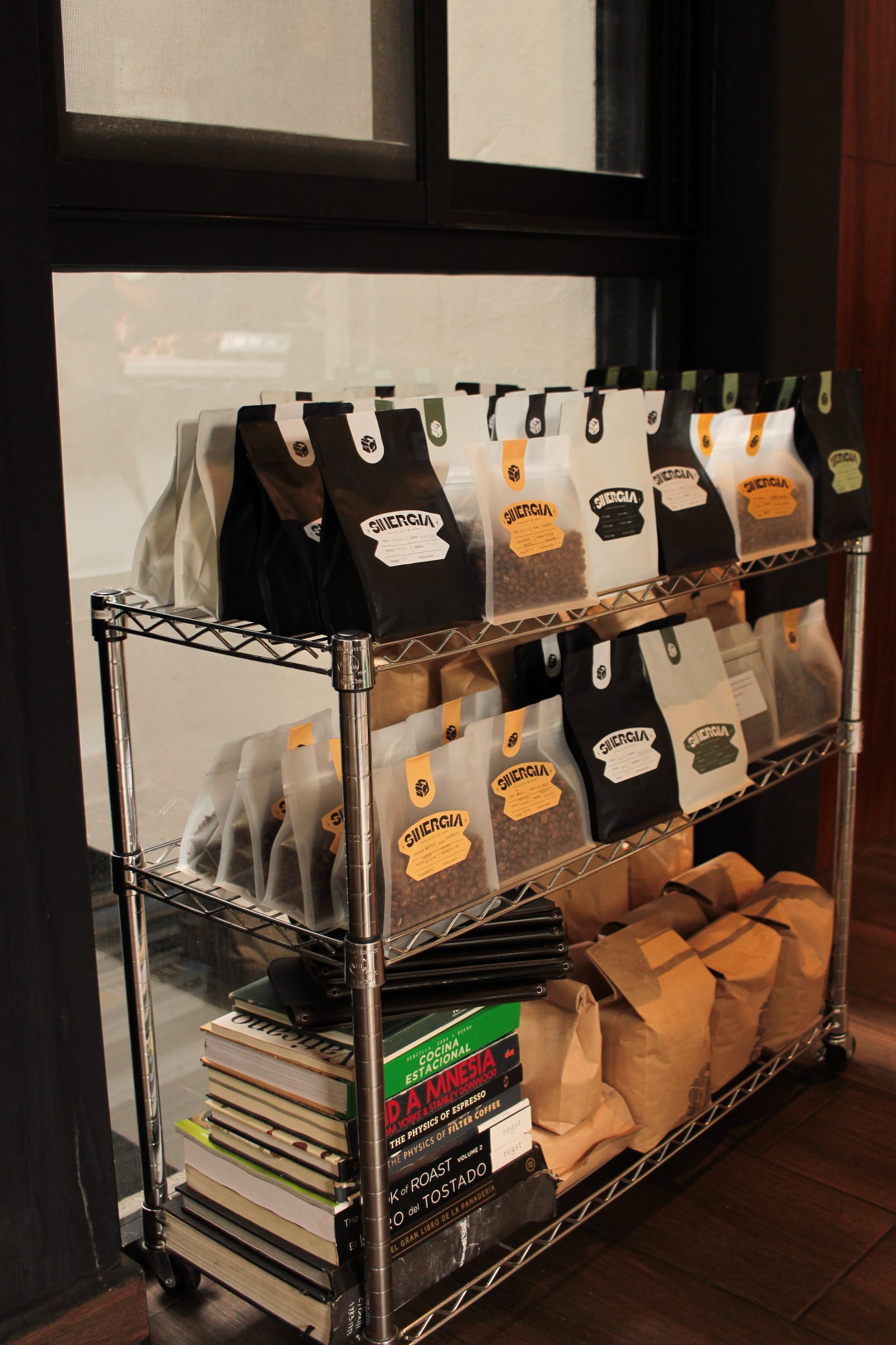 Estante de la tienda con bolsas de café, libros y bolsas de papel para llevar